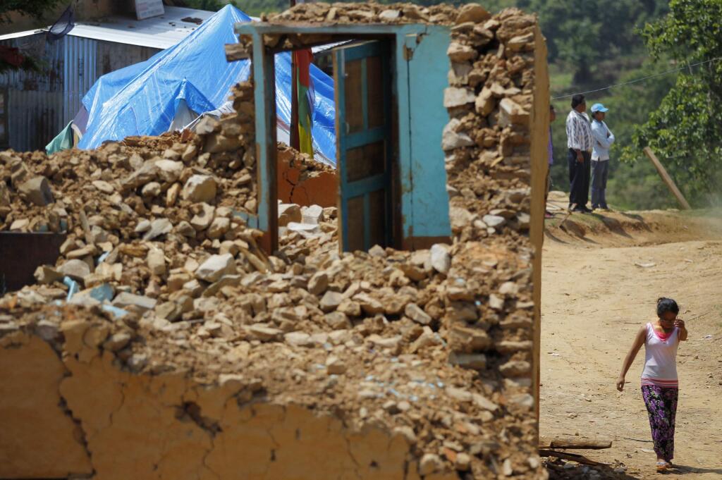 A Nepalese woman walks near a house damaged in last months earthquake on the outskirts of Lalitpur, Nepal, Monday, May 11, 2015. The April 25 earthquake killed more than 8,000 people and left thousands more homeless, as it flattened mountain villages and destroyed buildings and archaeological sites in the Himalayan region. (AP Photo/Niranjan Shrestha