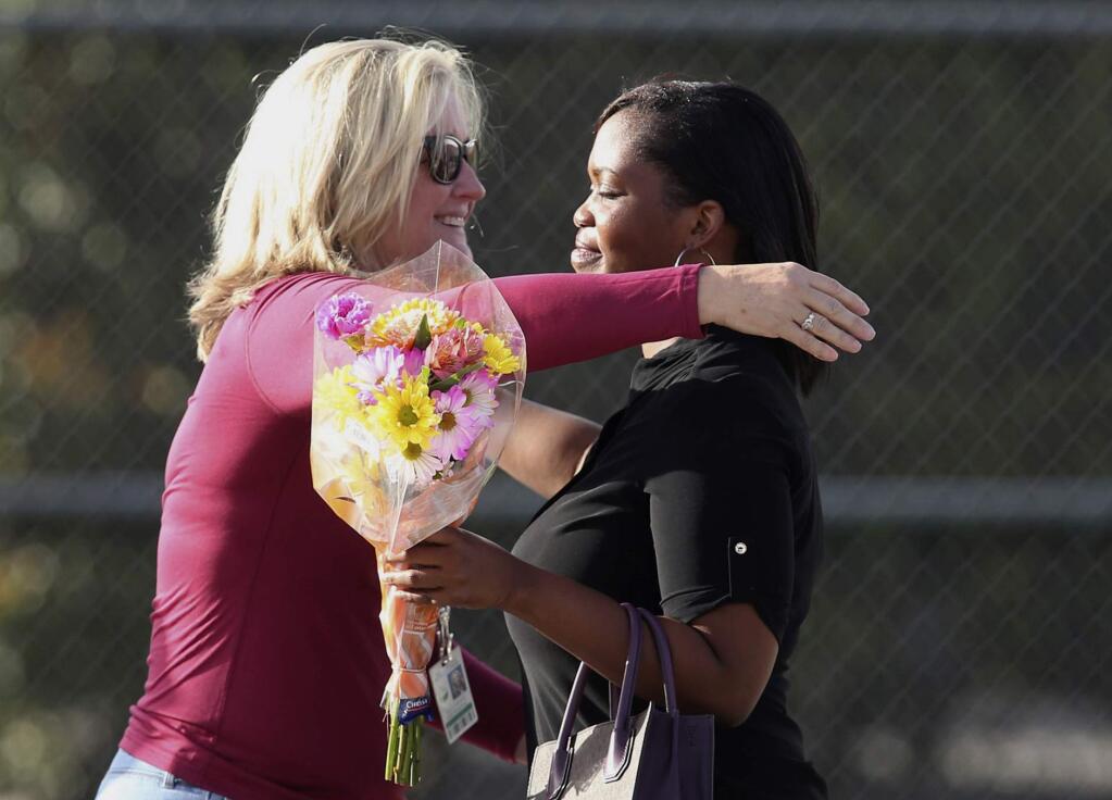 Marjory Stoneman Douglas High School assistant principal Denise Reed hugs a school employee as she returns to the school, Friday, Feb. 23, 2018. Following the shooting last week, the building where several students, a teacher, a football coach and the school's athletic director were slain will be torn down. Before that happens, 30 classrooms must be cleared of teaching materials, personal items and memories. (Charles Trainor Jr/Miami Herald via AP)