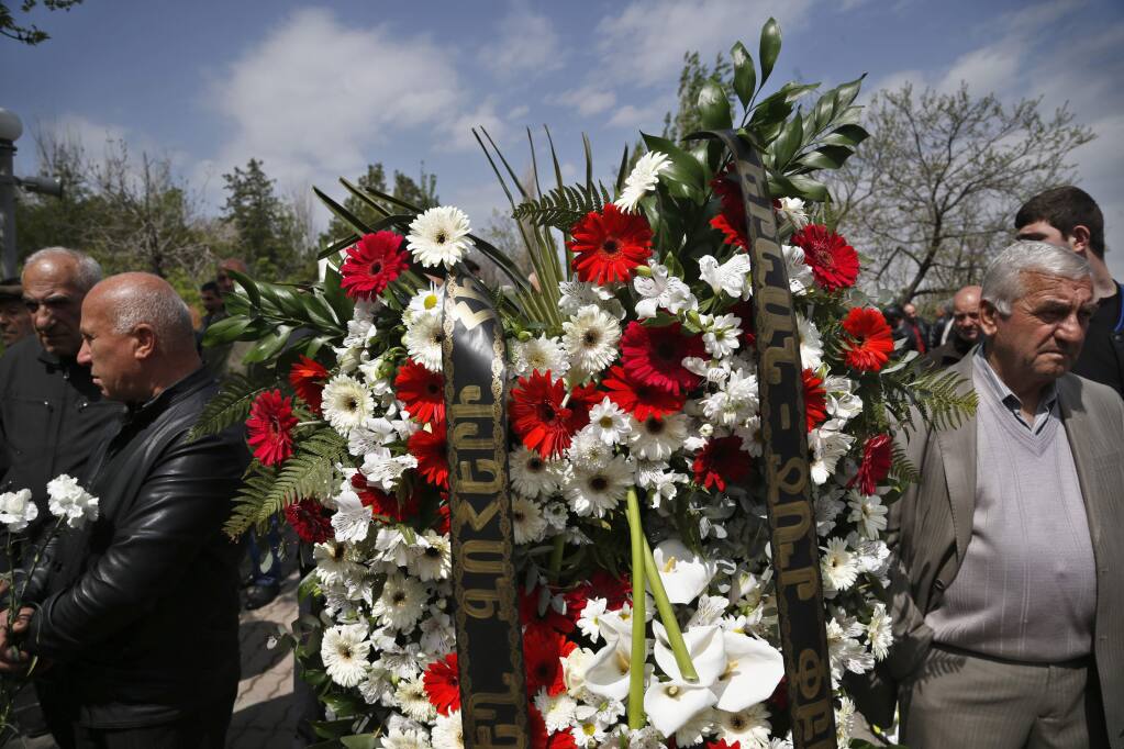 Armenians gather to lay flowers at a memorial to victims of massacres as they mark the centenary anniversary of the mass killings, in Yerevan, Armenia, Thursday, April 23, 2015. On Friday, April 24, Armenians will mark the centenary of what historians estimate to be the slaughter of up to 1.5 million Armenians by Ottoman Turks, an event widely viewed by scholars as genocide. Turkey, however, denies the deaths constituted genocide and says the death toll has been inflated. (AP Photo/Sergei Grits)