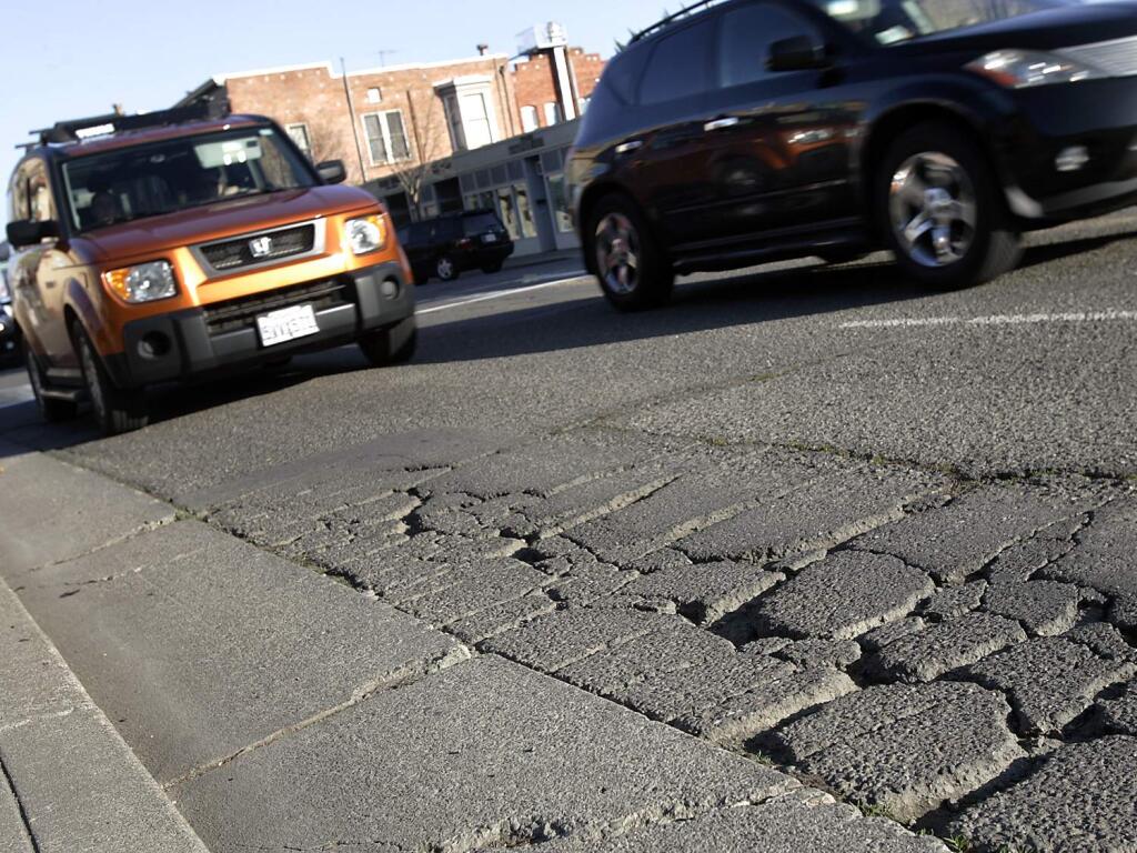 Vehicles approach potholes along Washington Street, west of Petaluma Boulevard North, in Petaluma. (Christopher Chung / PD File)