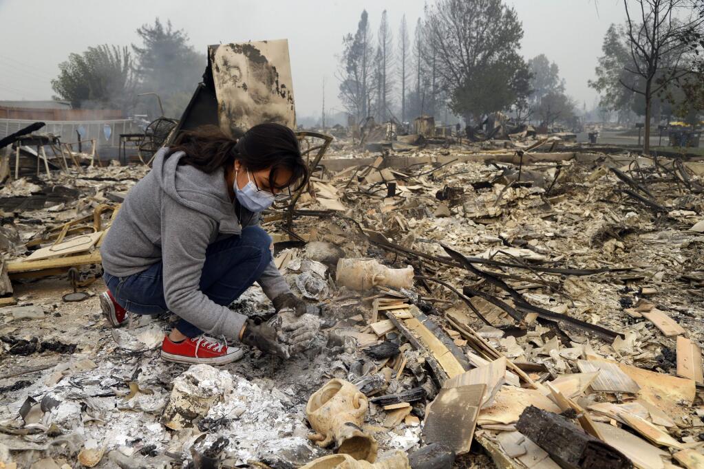 Leslie Garnica searches for belongings in the ashes of her home that was destroyed by fire in the Coffey Park area of Santa Rosa, Calif., on Tuesday, Oct. 10, 2017. An onslaught of wildfires across a wide swath of Northern California broke out almost simultaneously then grew exponentially, swallowing up properties from wineries to trailer parks and tearing through both tiny rural towns and urban subdivisions. (AP Photo/Ben Margot)