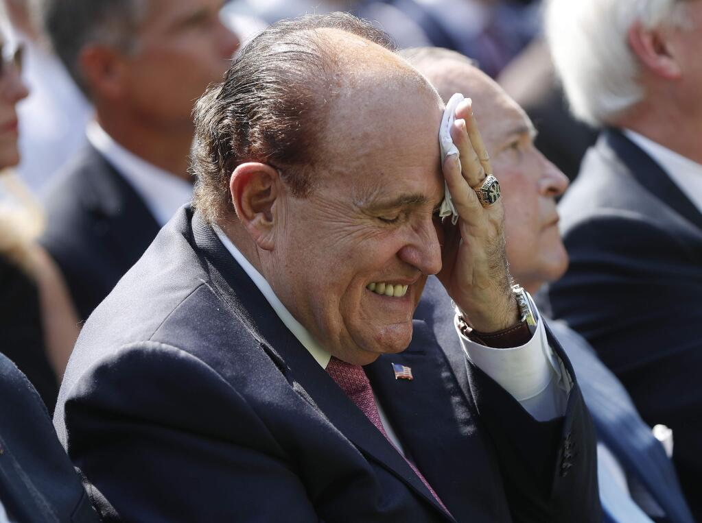 FILE - In this July 29, 2019 file photo, Rudy Giuliani, an attorney for President Donald Trump, left, wipes his forehead as he listens to President Donald Trump speak in the Rose Garden of the White House in Washington. (AP Photo/Pablo Martinez Monsivais)
