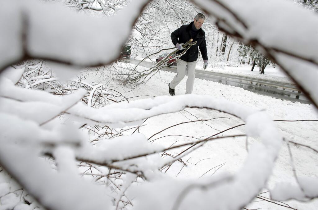 Kevin Crowley, of Weyland, Mass., works to remove damaged tree branches from a driveway, Thursday, March 8, 2018, in Sherborn, Mass. For the second time in less than a week, a storm rolled into the Northeast with wet, heavy snow Wednesday and Thursday, grounding flights, closing schools and bringing another round of power outages to a corner of the country still recovering from the previous blast of winter. (AP Photo/Steven Senne)