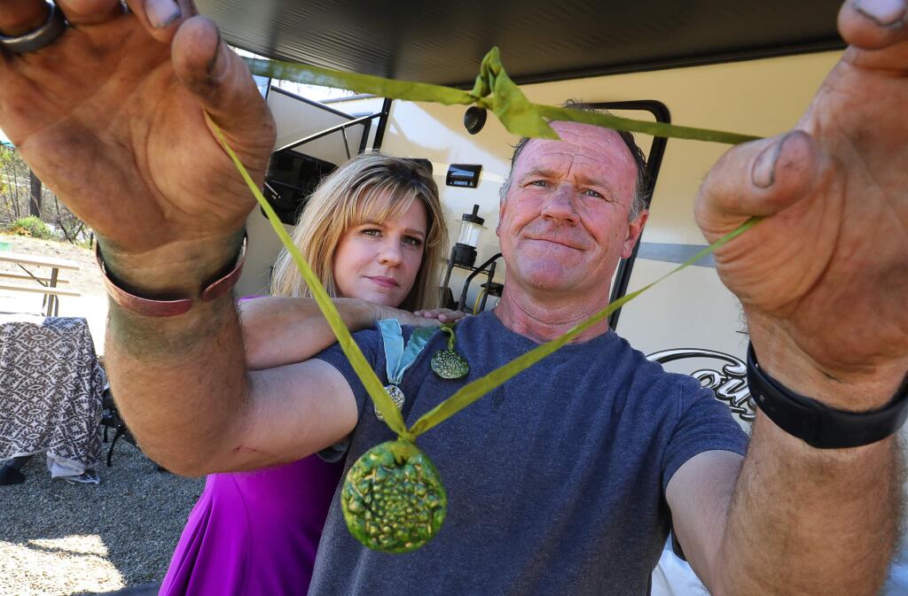Colleen and John Thill, who lost their Coffey Park home in the Tubbs fire, received an unexpected gift from a stranger, Wendy Anderson, who took a pine cone from a tree at the burned house and used it to make clay and epoxy pendants. Collen had put up a message on the tree to save it, because it is the only thing at their home that survived the fire.(Christopher Chung/ The Press Democrat)