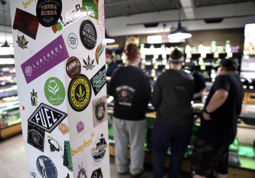 Marijuana brand name stickers are visible as customers line up at the counter in CannaDaddy's Wellness Center marijuana dispensary in Portland, Ore., Thursday, April 20, 2017. Thursday marks marijuana culture's high holiday, 4/20, and it's falling this year as the U.S. government takes a harder look at pot policy and as more states have legalized the drug. (AP Photo/Don Ryan)