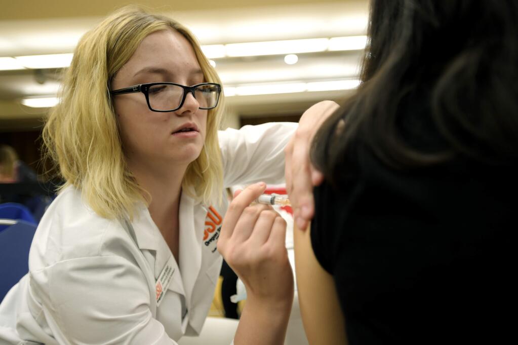 FILE - In this Nov. 8, 2017 file photo, Jordan Feist, a second year pharmacy doctorate student at Oregon State University, administers a meningococcal vaccine to freshman Jessica Aimecki at a clinic on campus in Corvallis, Ore. An outbreak of meningococcal disease at Oregon State University is officially over. The university recorded five cases of the same strain of the potentially deadly disease over a 12-month span beginning in November 2016. (Amanda Loman/Albany Democrat-Herald via AP, File)