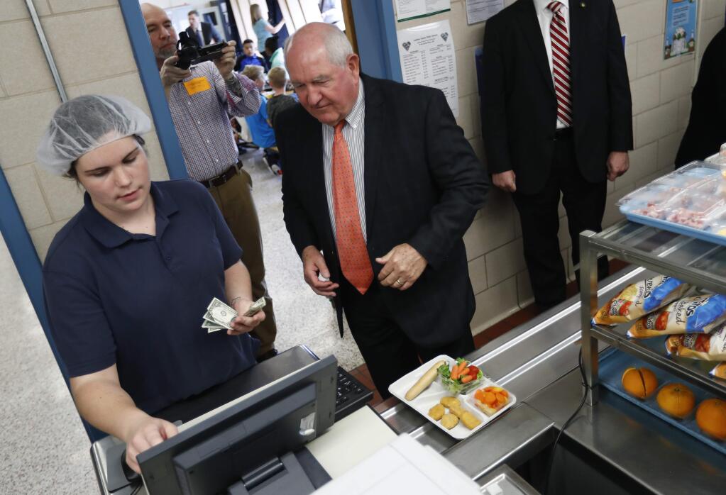 Agriculture Secretary Sonny Perdue pays for his lunch in the Catoctin Elementary School cafeteria in Leesburg, Va., Monday, May 1, 2017. After eating lunch with students Perdue unveiled a new rule on school lunches as the Trump administration and other Republicans press for flexibility after eight years of the Obama's emphasis on health eating. (AP Photo/Carolyn Kaster)