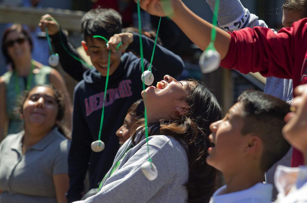 Vanessa Roman Martinez, center, competes in a donut eating contest during a rally at Roseland Collegiate Prep, who have taken over the site of the former Roseland University Prep after parts of their school were destroyed in the October wildfires. (photo by John Burgess/The Press Democrat)