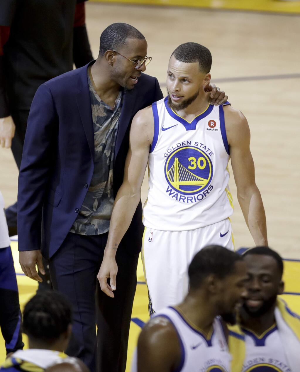 Golden State Warriors guard Stephen Curry (30) walks with injured forward Andre Iguodala, in suit, after scoring against the Cleveland Cavaliers during the first half of Game 1 of basketball's NBA Finals in Oakland, Calif., Thursday, May 31, 2018. (AP Photo/Marcio Jose Sanchez)