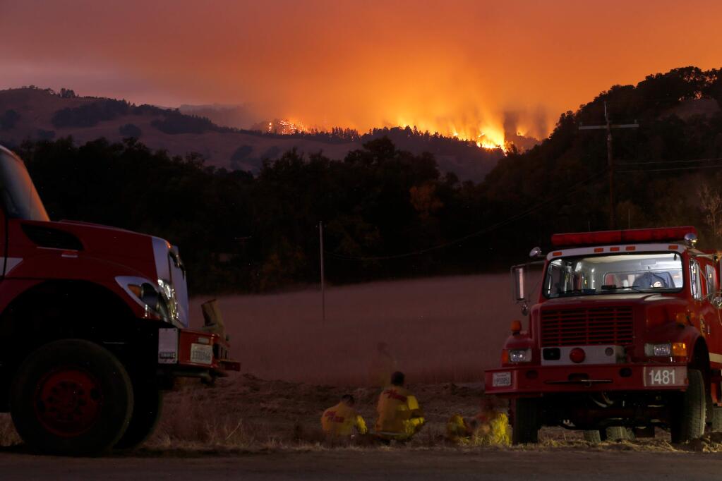 A strike team of Cal Fire firefighters watch the flames of the Kincade Fire from where they are staged near Healdsburg, California, awaiting the night's severe wind event on Saturday, October 26, 2019. (Alvin Jornada / The Press Democrat)