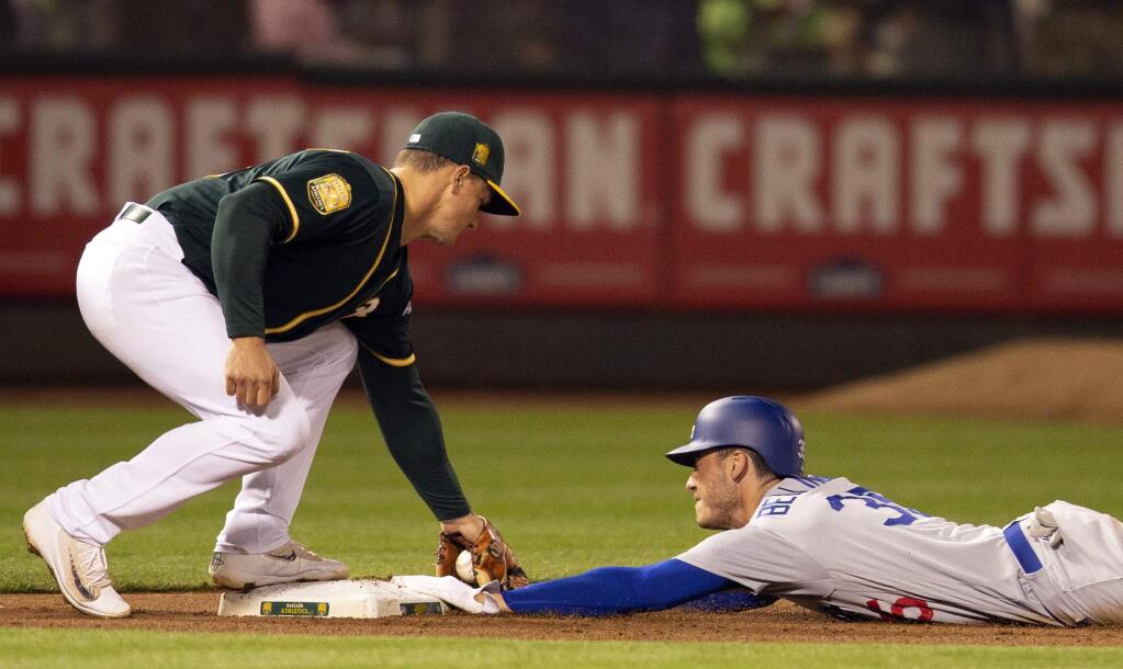 The Los Angeles Dodgers' Cody Bellinger slides safely under the tag of Oakland Athletics third baseman Matt Chapman during the inning Tuesday, Aug. 7, 2018, in Oakland. Bellinger went from first to third on a single by Yasiel Puig. (AP Photo/D. Ross Cameron)