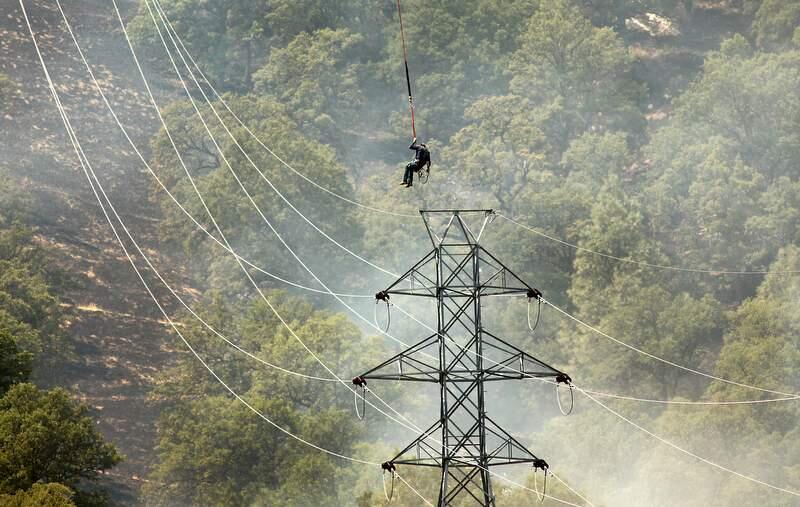 A PG&E workers is lowered onto power lines on the lines of the Wye fire near Clearlake Oaks on Monday, August 13, 2012.