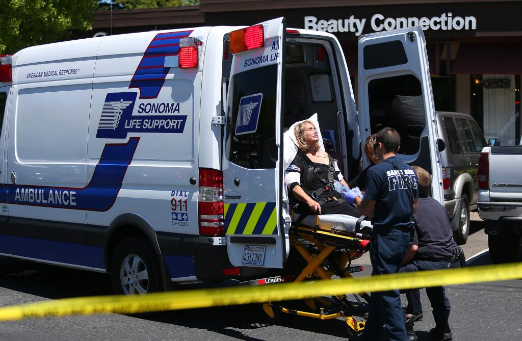 Emergency personnel load employee Suzanne Dodd, injured in the robbery of Bennett Valley Jewelers in Santa Rosa, into an ambulance on Thursday, July 10, 2014. (Christopher Chung/ The Press Democrat)