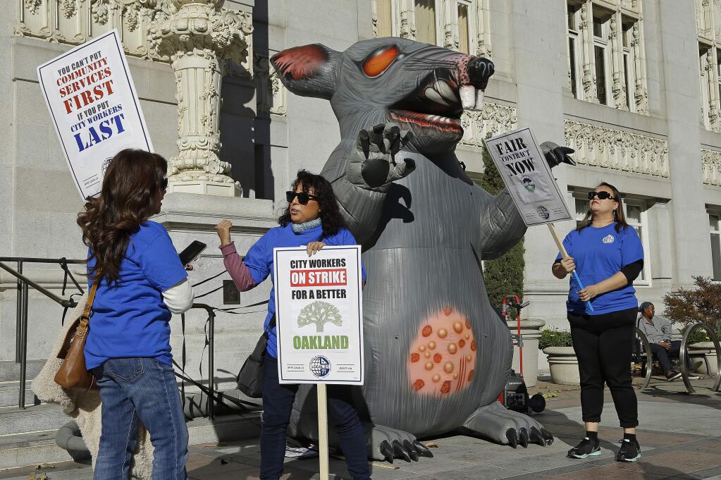 City of Oakland workers picket beside an inflatable rat in front of City Hall on Tuesday, Dec. 5, 2017, in Oakland, Calif. (AP Photo/Ben Margot)