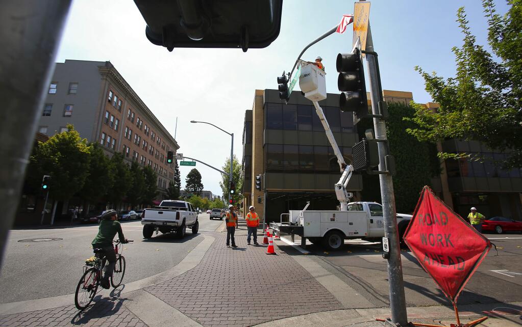 A crew from Mike Brown Electric installs a left turn yield sign at Fifth Street and Mendocino Avenue, in Santa Rosa, on Wednesday, July 27, 2016. 5th Street is converting to a two-way street from a one-way street due to the reunification of Courthouse Square.(Christopher Chung/ The Press Democrat)