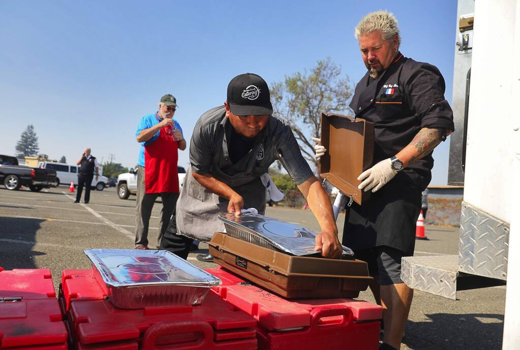 Celebrity chef Guy Fieri, right, and Cesar Orozco pack bins with food to be delivered to area evacuation centers by the Salvation Army, behind the Veterans Memorial building in Santa Rosa on Thursday, October 12, 2017. (Christopher Chung/ The Press Democrat)