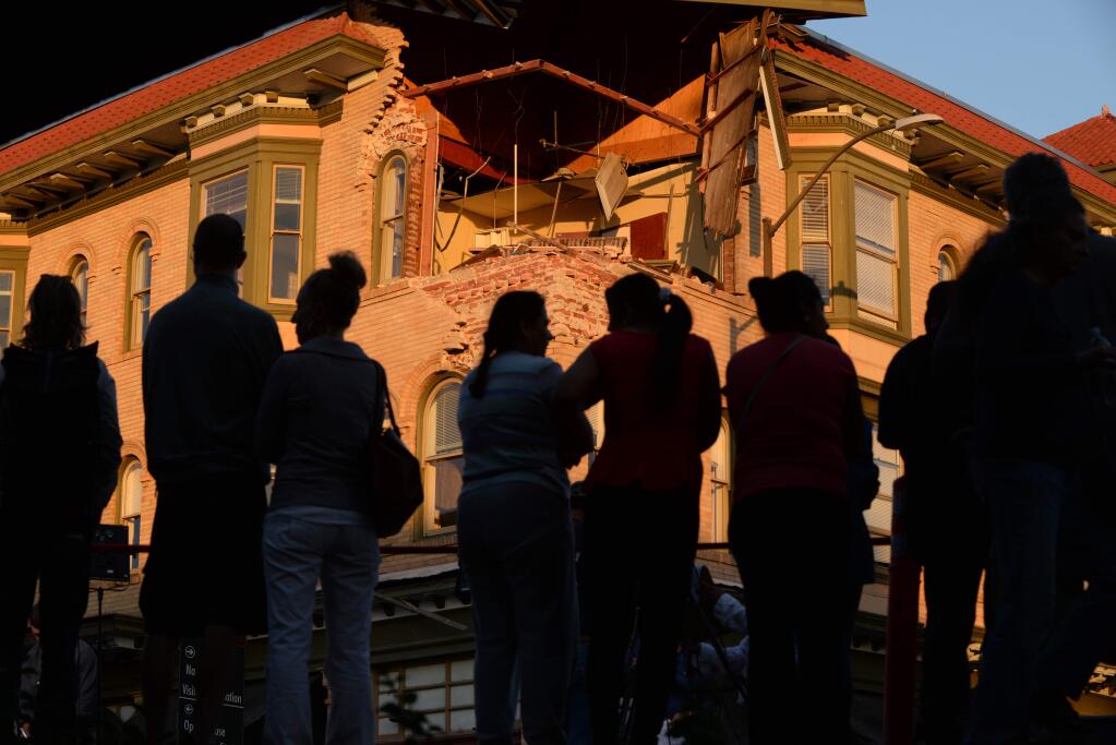 A constant crowd came and went at the corner of Brown and Second streets in downtown Napa to get a close up look at the damage done by the early morning quake. 'Wow, this is unbelievable,' said Napa resident Eddie Henry, 49, when he came downtown with his wife and two stepchildren to see the damage. August 24, 2014. (Photo: Erik Castro/for The Press Democrat)