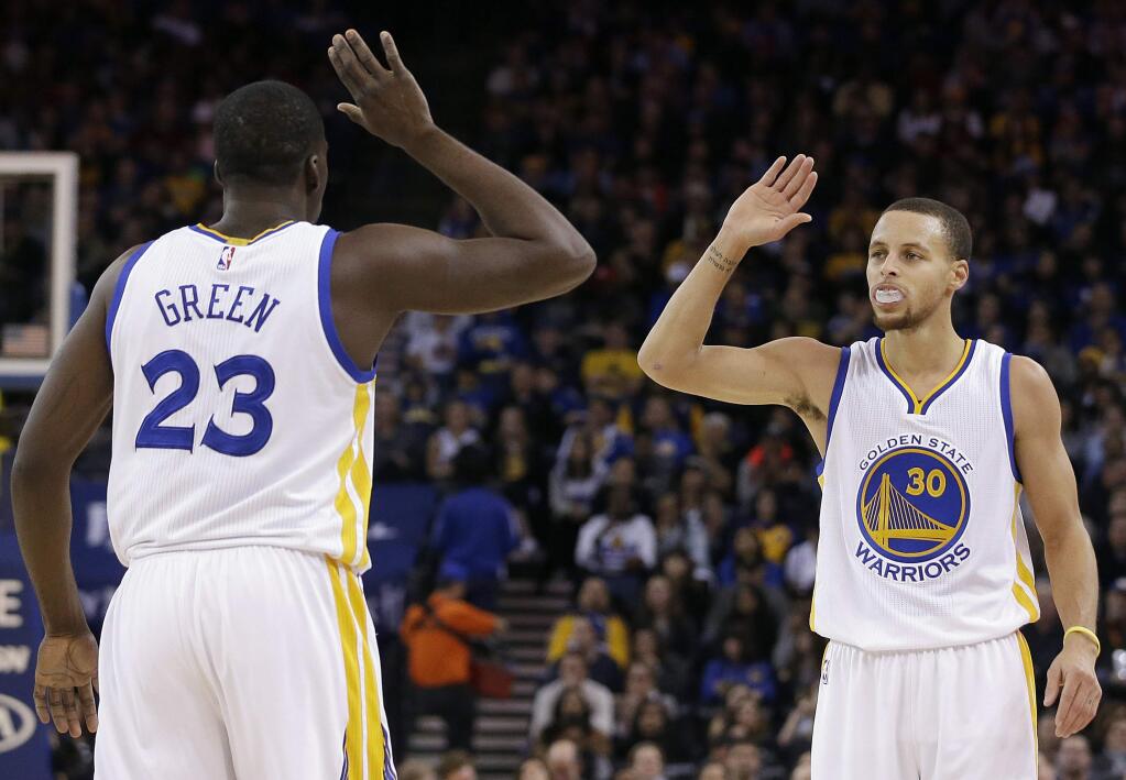 Golden State Warriors forward Draymond Green (23) and guard Stephen Curry (30) greet during the first half of a game against the Philadelphia 76ers in Oakland, Tuesday, Dec. 30, 2014. The Warriors won 126-86. (AP Photo/Jeff Chiu)