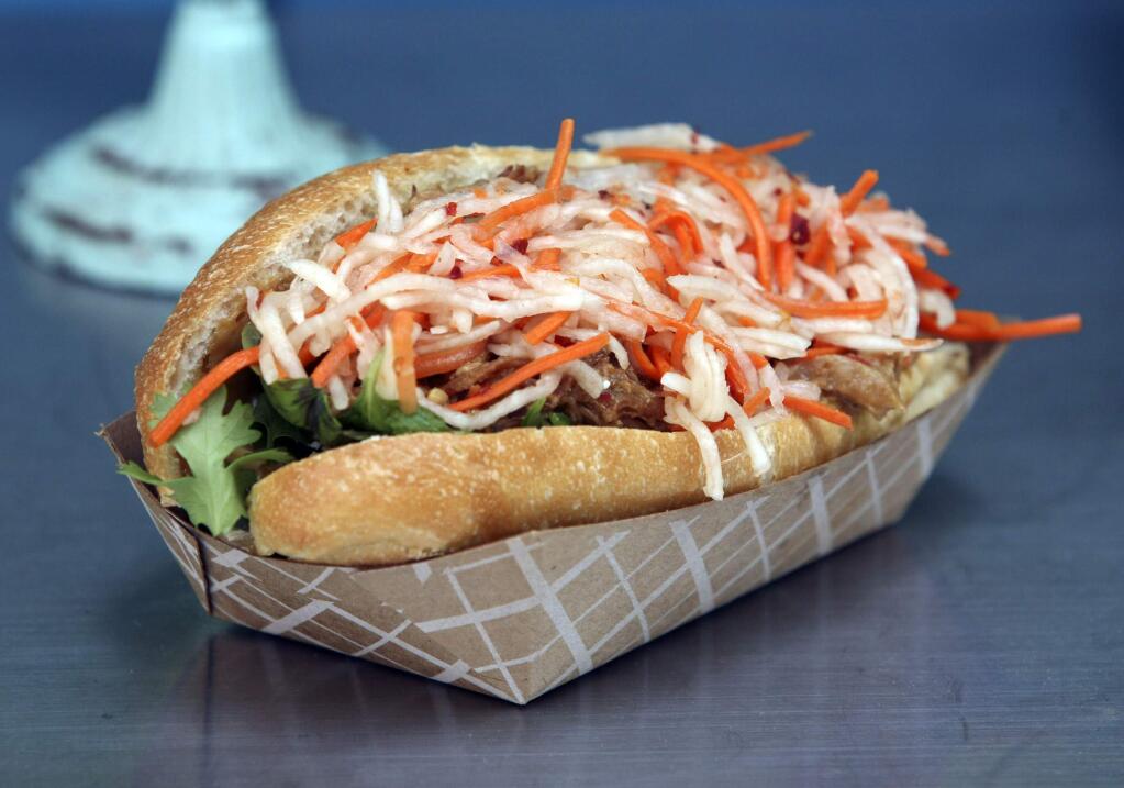 A Banh Mi sandwich made of roasted pork, pickled carrots and Daikon, cilantro, mint, peanuts, and secret sauce on a Full circle Bakery torpedo roll at the Secret Kitchen Behind Agius Market at the corner of Bodega Ave. and Skillman lane in Petaluma on Friday September 19, 2014. (SCOTT MANCHESTER/ARGUS-COURIER STAFF)