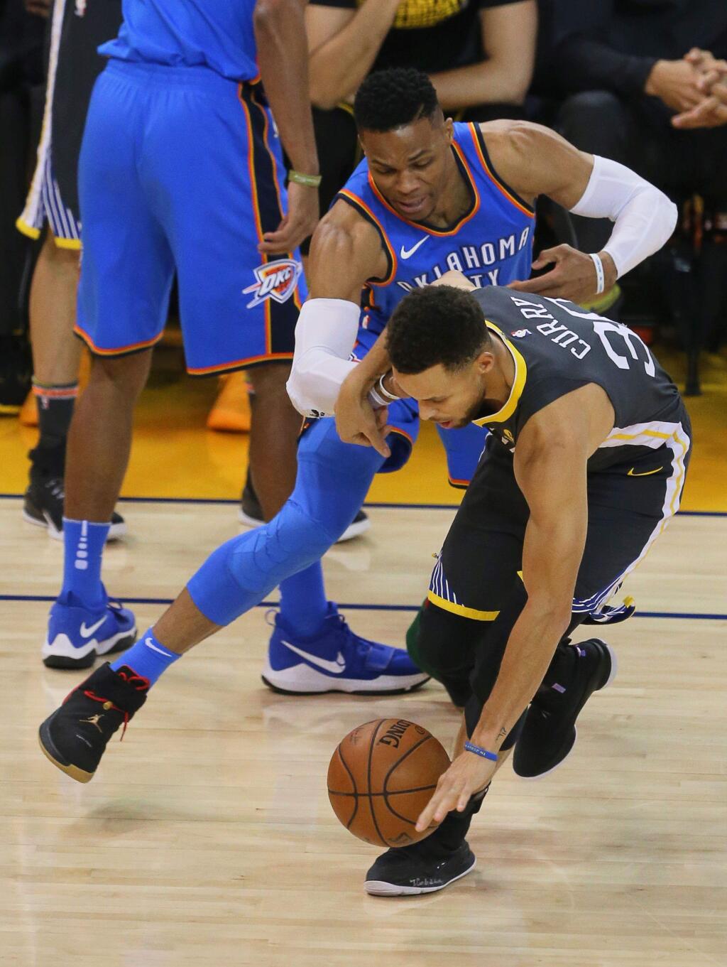 Golden State Warriors guard Stephen Curry loses the ball while trying to drive past Oklahoma City Thunder guard Russell Westbrook in Oakland on Tuesday, Feb. 6, 2018. (Christopher Chung / The Press Democrat)