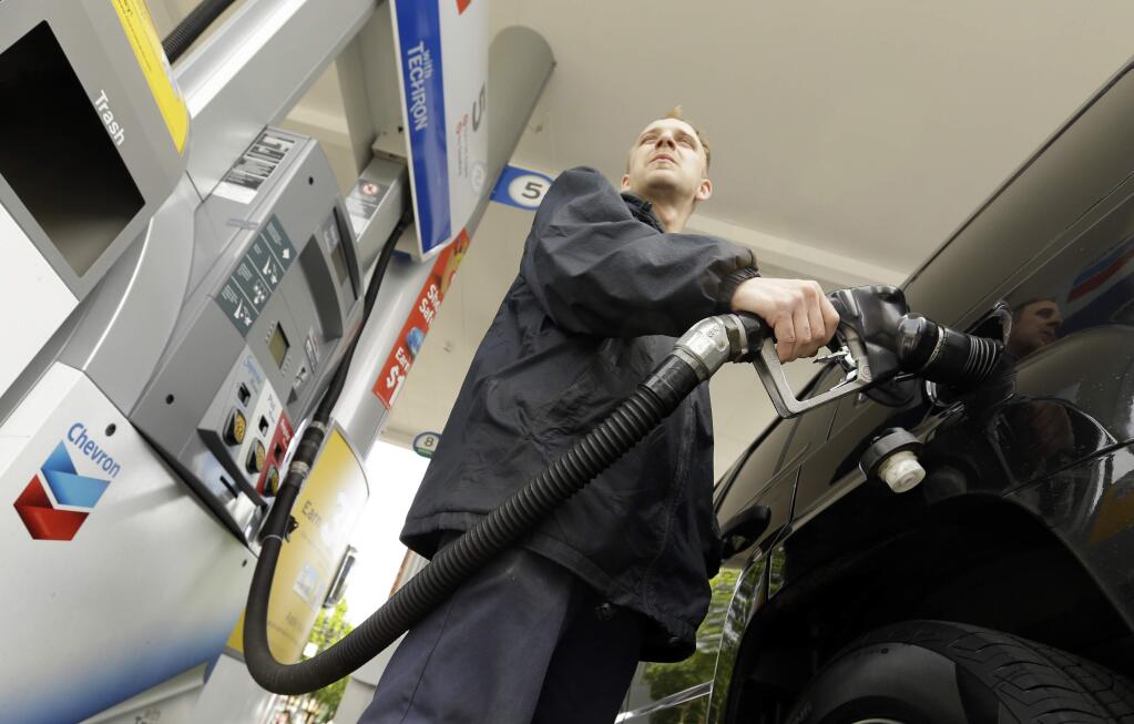 FILE- In this May 6, 2015 file photo, attendant James Lewis pumps gas at a station in Portland, Ore. Oregon lawmakers are rolling out a 10-year transportation package that would raise consumer prices at the gas pump and when buying a new car and impose highway tolls for the first time along with a 5 percent tax on new bicycles and higher registration fees for fuel-efficient cars. (AP Photo/Don Ryan, File)