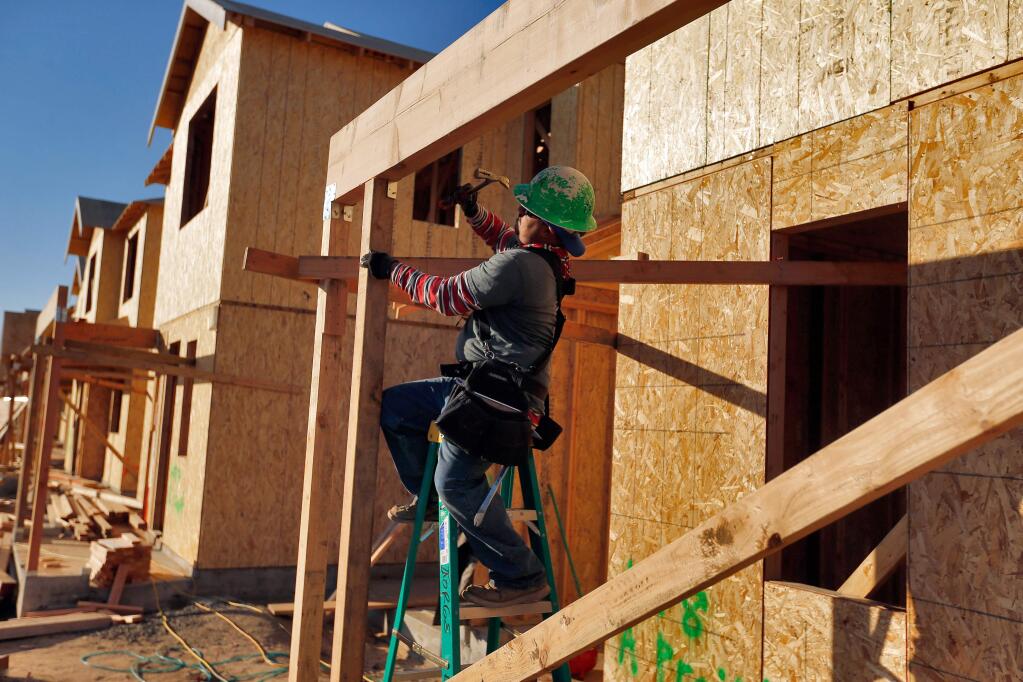 Carpenter Salvador Ponce works on the front porch of one of the new homes being built on Bay Village Avenue in Santa Rosa on Dec. 29. (ALVIN JORNADA / The Press Democrat)