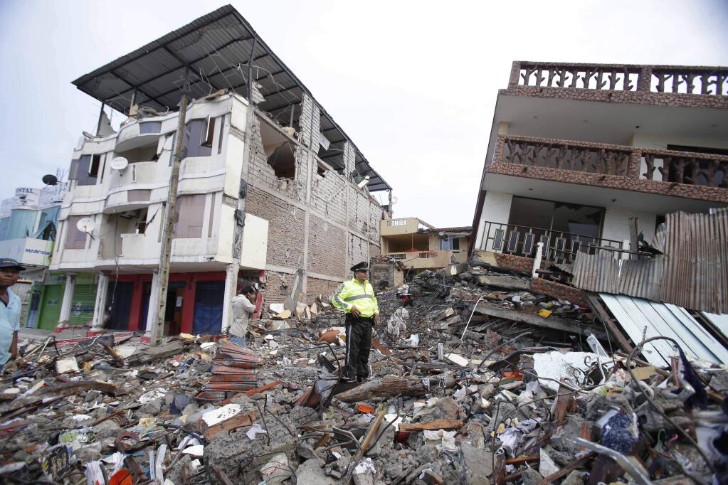 A police officer stands on debris, next to buildings destroyed by an earthquake in Pedernales, Ecuador, Sunday, April 17, 2016. The strongest earthquake to hit Ecuador in decades flattened buildings and buckled highways along its Pacific coast, sending the Andean nation into a state of emergency. (AP Photo/Dolores Ochoa)