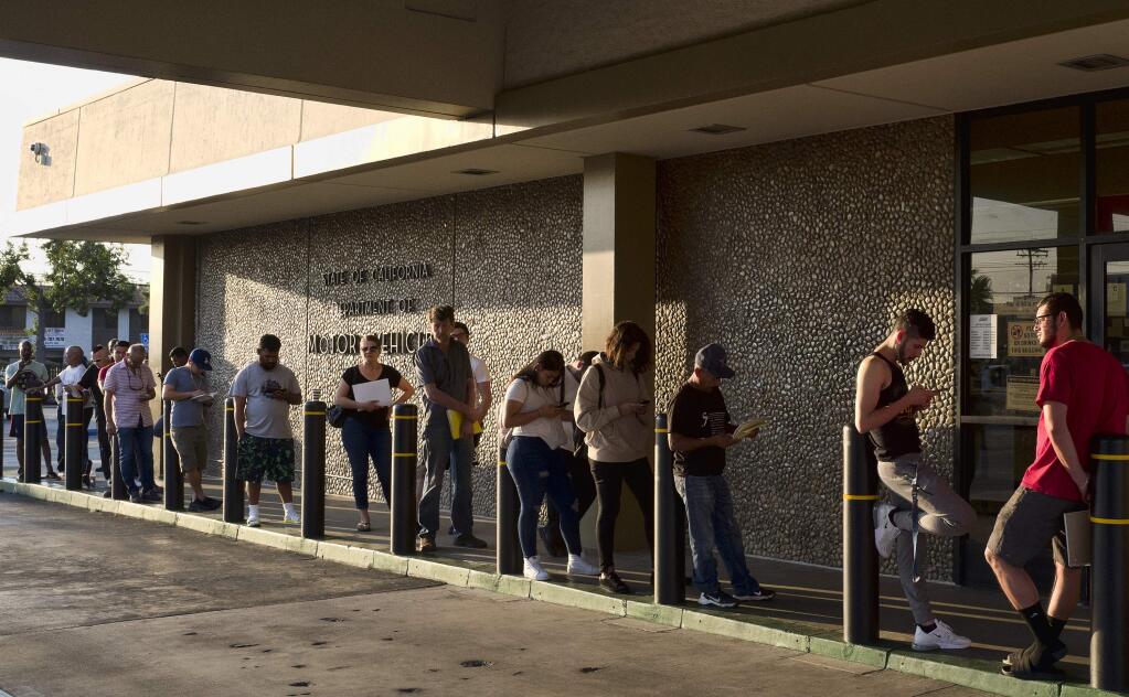 FILE - In this Tuesday, Aug. 7, 2018, file photo, people line up at the California Department of Motor Vehicles prior to opening in the Van Nuys section of Los Angeles. California Gov. Jerry Brown is ordering an audit the Department of Motor Vehicles in light of long wait times. The state's department of finance will perform the audit, looking into information technology and customer service.A Friday, Sept. 21, 2018, letter from Finance Director Keely Bosler tells DMV Director Jean Shiomoto the audit will assess information technology and customer service. (AP Photo/Richard Vogel, File)
