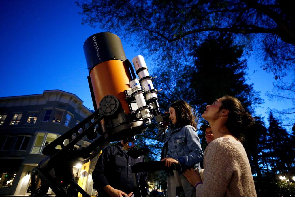 Heavenly Swendsen, right, of Campbell looks into the sky while he daughter Pascale, 7, peers at the moon through one of the telescopes set up by Dan and Bill Gordon of Night Sky Adventure, in Healdsburg, California, on Friday, March 15, 2019. (Alvin Jornada / The Press Democrat)