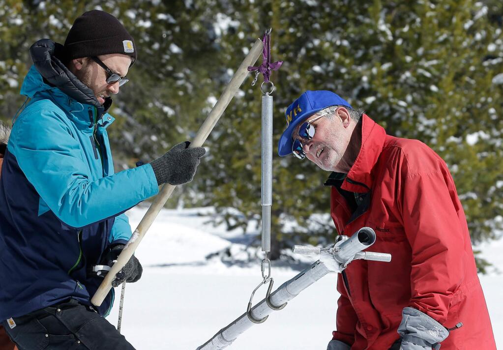 File - In this March 5, 2018, file photo, Frank Gehrke, chief of the California Cooperative Snow Surveys Program for the Department of Water Resources, right, reads the weight of the snow sample, on a scale held by Dylan Chapple, a fellow with the California Council of Science and Technology, during a supplemental snow survey near Echo Summit, Calif. Californians close out their rainy season with the break they were hoping for, as a series of late-winter storms ease drought conditions that had been setting in again. (AP Photo/Rich Pedroncelli, File)