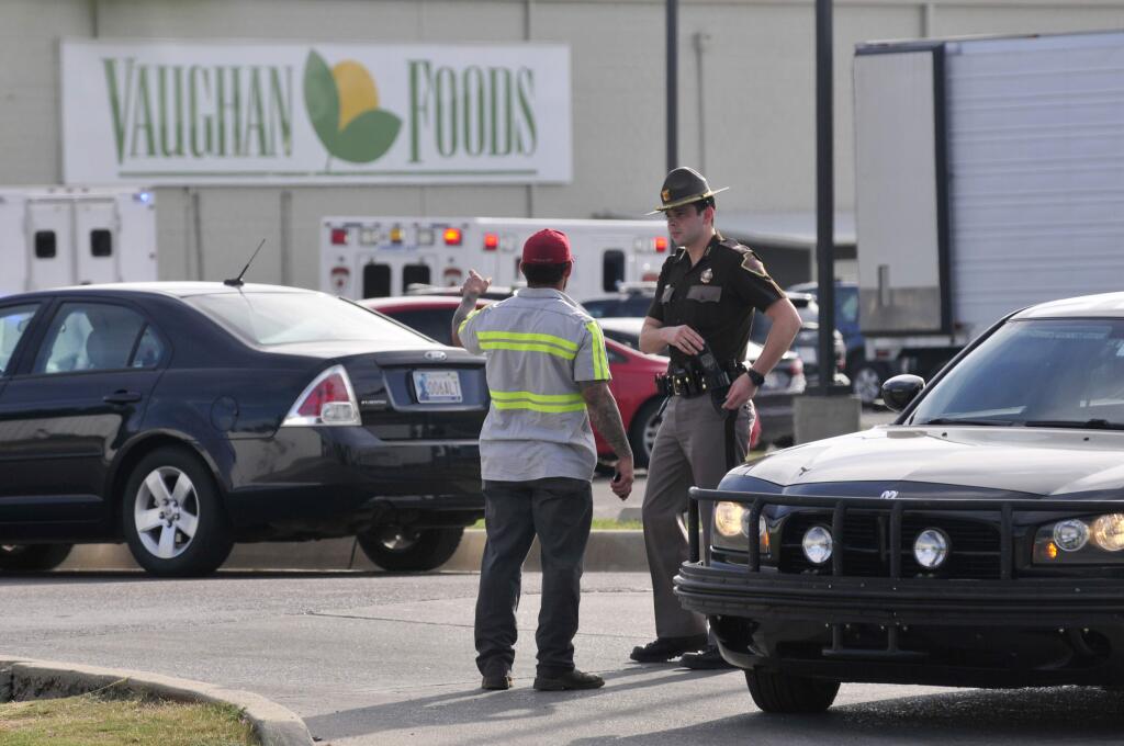 An Oklahoma State Trooper help secure the scene at Vaughan Foods as police try to piece together what happened after one person was stabbed to death and another person, believed to be the alleged assailant, was shot multiple times by an off duty police officer at the food distribution plant in Moore, Okla., Thursday, Sept. 25, 2014. (AP Photo / The Norman Transcript, Kyle Phillips)