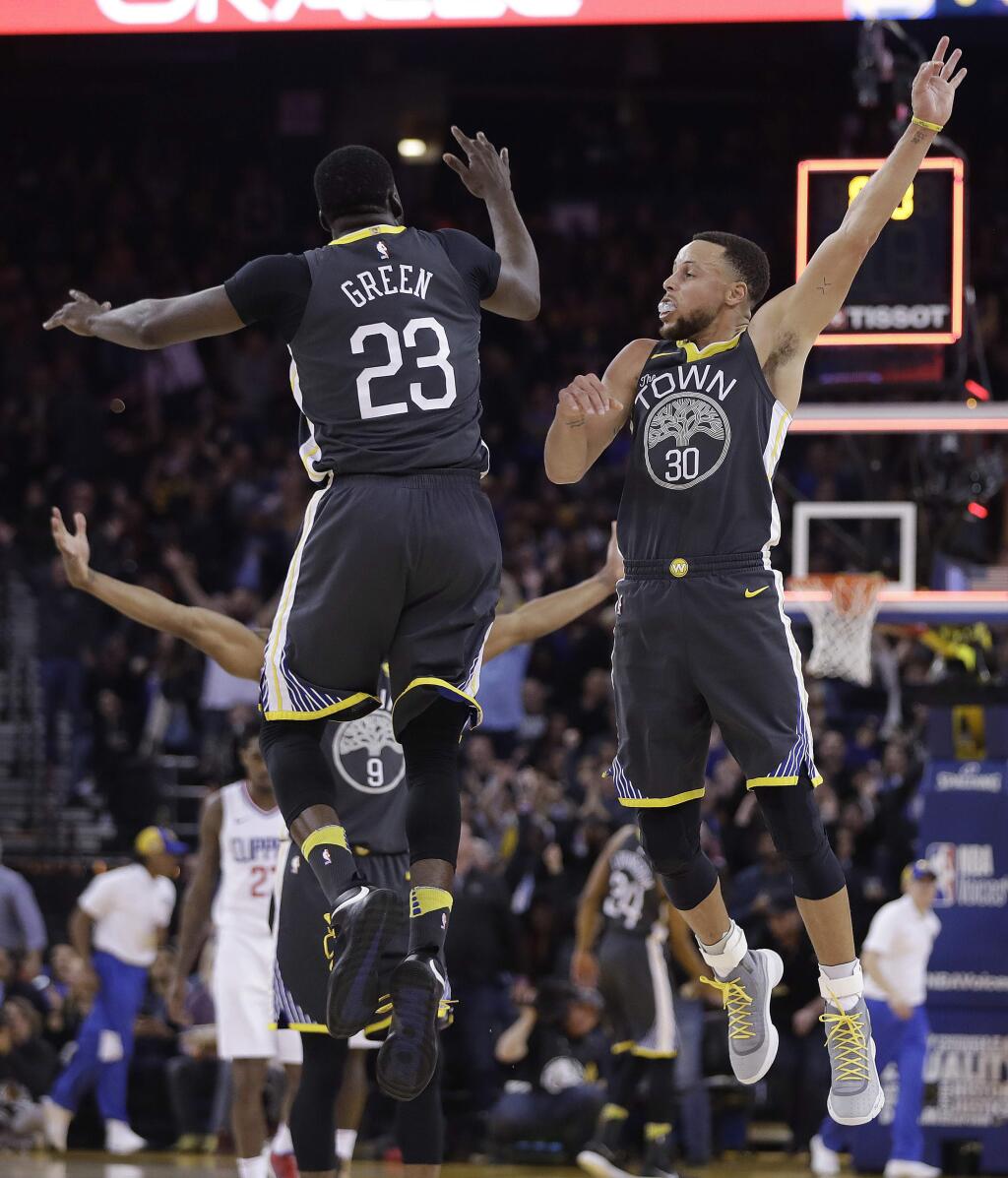 Golden State Warriors' Stephen Curry (30) celebrates with Draymond Green (23) after Curry hit a 3-pointer at the buzzer during the first quarter of an NBA basketball game against the Los Angeles Clippers on Thursday, Feb. 22, 2018, in Oakland, Calif. (AP Photo/Marcio Jose Sanchez)