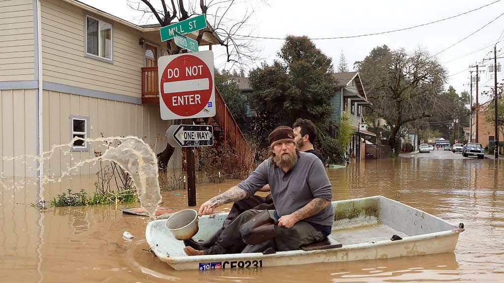 Jonathan Von Renner Jr., and a friend row past Mill and Third Street in Guerneville, Wednesday, Feb. 27, 2019. (Kent Porter | The Press Democrat)