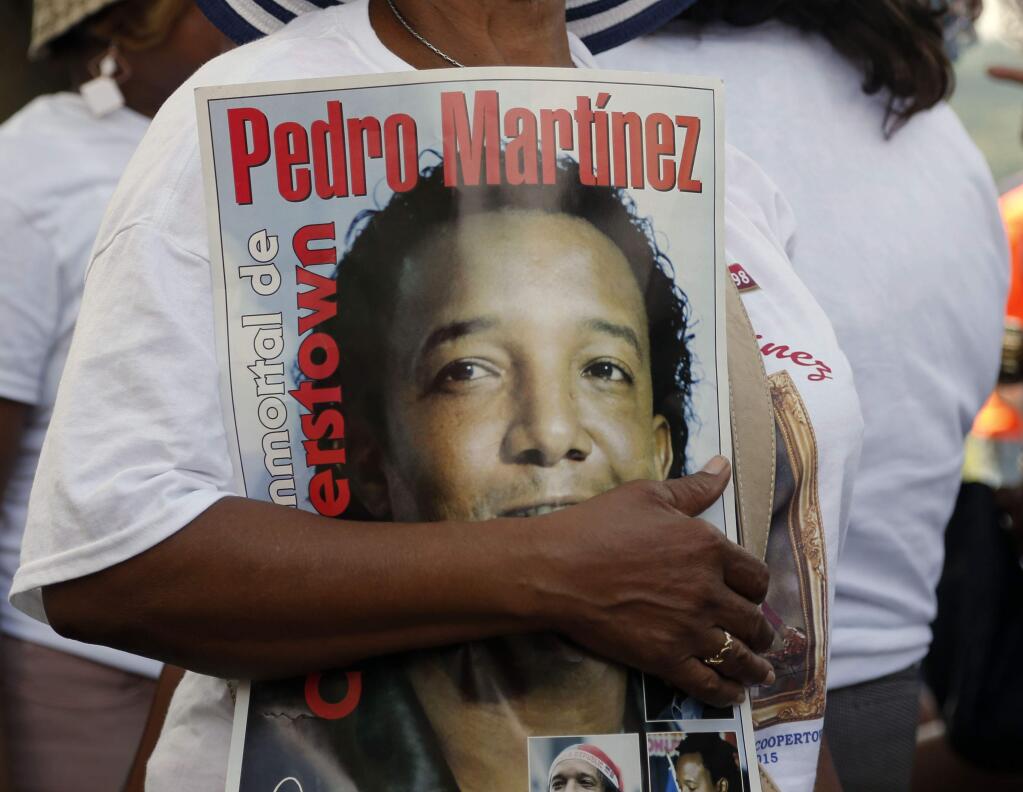 A Pedro Martinez fan carries a poster at the Clark Sports Center before the National Baseball Hall of Fame induction ceremony on Sunday, July 26, 2015, in Cooperstown, N.Y. Martinez will be inducted to the hall Sunday afternoon. (AP Photo/Mike Groll)