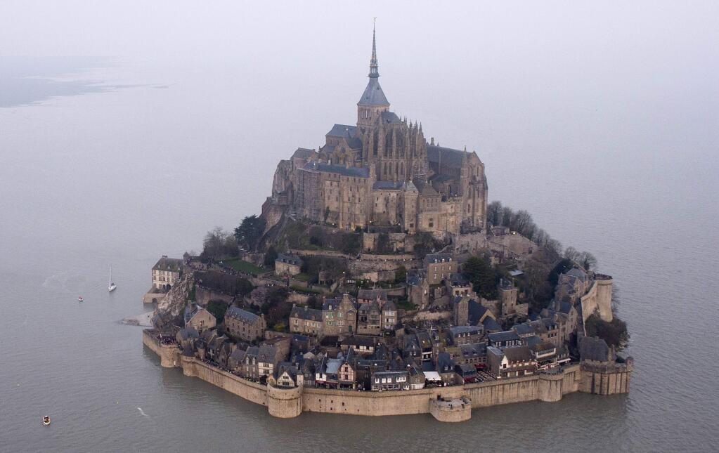 FILE - In this March 21, 2015 file photo, a high tide submerges a narrow causeway leading to the Mont Saint-Michel, on France's northern coast. Authorities are evacuating tourists and others from the Mont-Saint-Michel abbey and monument in western France on Sunday April 22, 2018, after a visitor apparently threatened to attack security services. (AP Photo) FRANCE OUT