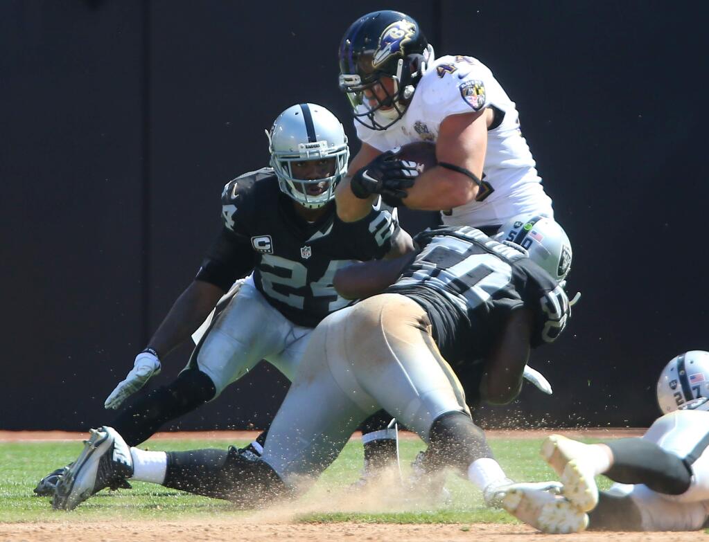 Baltimore Ravens fullback Kyle Juszczyk is tackled by Oakland Raiders linebacker Curtis Lofton, with help by cornerback Charles Woodson, during their game in Oakland on Sunday, September 20, 2015. The Raiders defeated the Ravens 37-33.(Christopher Chung/ The Press Democrat)
