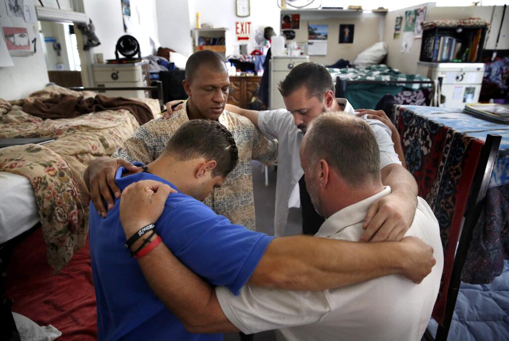 (Clockwise from front left) Kevin Cassidy, Charles Washington, Jameson McMillian, and Mark Mullis pray together in their dormitory room at the Redwood Gospel Mission in Santa Rosa, on Thursday, July 14, 2016. (BETH SCHLANKER/ The Press Democrat)