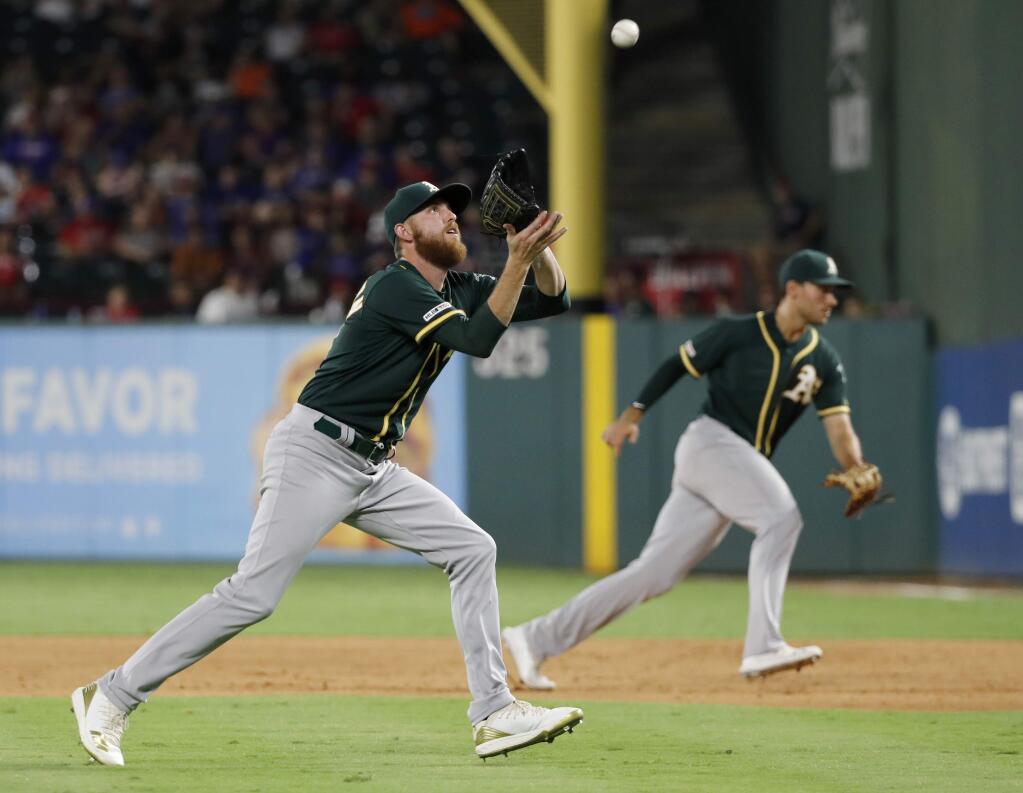 Oakland A's relief pitcher Paul Blackburn, left, reaches to field a groundout by the Texas Rangers' Rougned Odor as first baseman Matt Olson, rear, moves to cover first in the fourth inning in Arlington, Texas, Saturday, Sept. 14, 2019. (AP Photo/Tony Gutierrez)