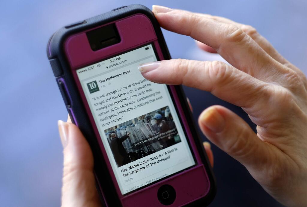 In this Tuesday, April 28, 2015 photo, an unidentified person uses a mobile phone to read the news from The Huffington Post on Facebook, in Los Angeles. State of the News Media 2015, published Wednesday, April 29, 2015, by the Pew Research Centers Journalism Project found that nearly half of Web users learn about politics and government from Facebook, roughly the same percentage as those who seek the news through local television and double those who visit Yahoo or Google News. (AP Photo/Richard Vogel)