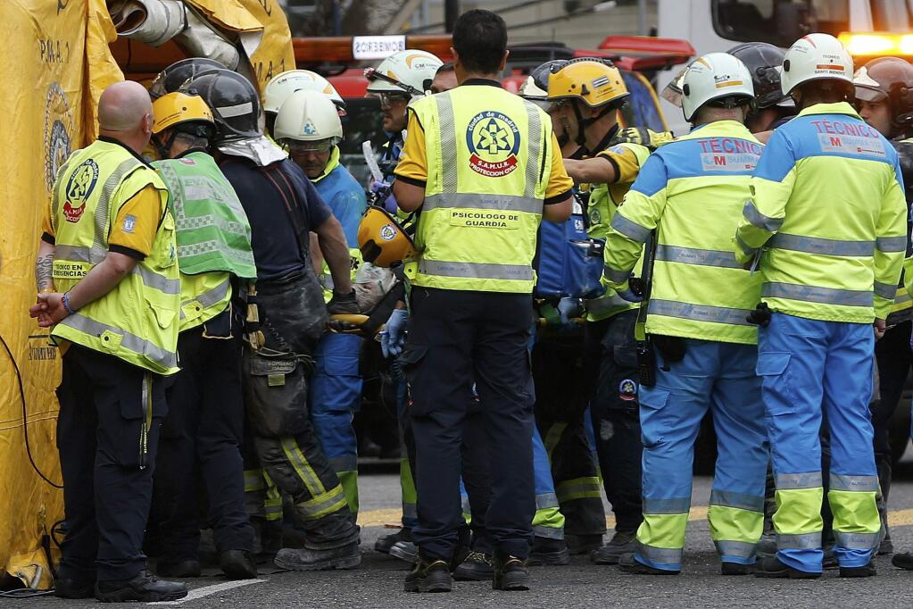 An injured worker is carried on a stretcher after scaffolding collapsed at the Ritz hotel undergoing renovation in Madrid, Spain, Tuesday, Sept. 18, 2018. One construction worker was killed and at least 11 injured after wrought iron work on the sixth floor of the hotel collapsed dragging down five floors of internal scaffolding and the workers at the site. (AP Photo/Paul White)