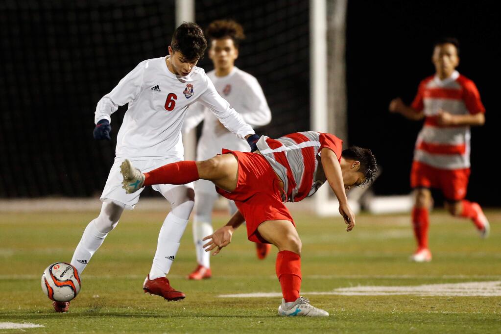 Rancho Cotate's Alex Sandoval (6), left, knocks over Montgomery's Bryan Rosales (6), center, during the first half of a boys varsity soccer match between Montgomery and Rancho Cotate high schools in Rohnert Park, California, on Wednesday, January 17, 2018. (Alvin Jornada / The Press Democrat)