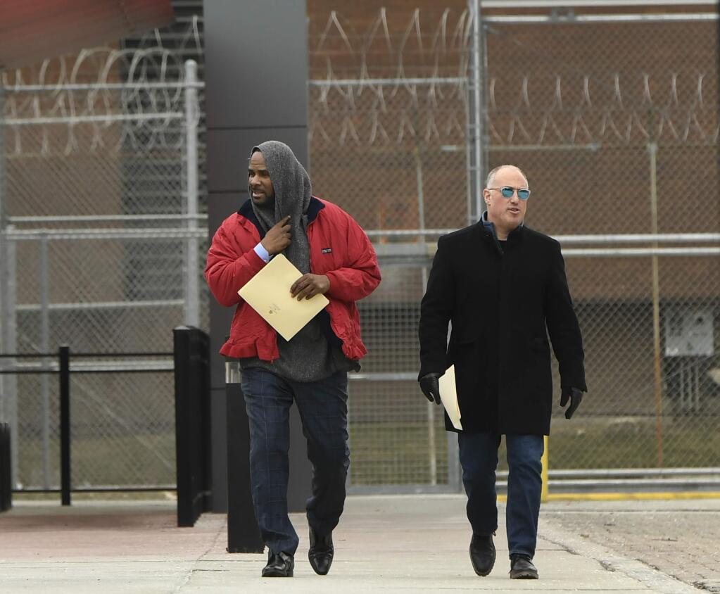 Singer R. Kelly left, walks with his attorney Steve Greenberg right, after being released from Cook County Jail, March 9, 2019, in Chicago. Kelly was freed three days after a judge ordered him jailed until he paid the total amount of back child support that he owed. (AP Photo/Paul Beaty)