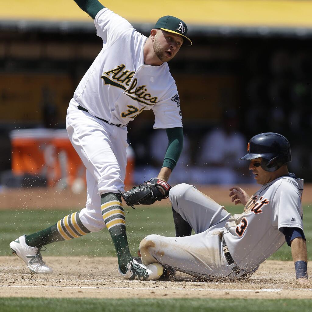Oakland Athletics pitcher Jesse Hahn, left, tags out Detroit Tigers' Ian Kinsler (3) at home plate in the fourth inning of a baseball game Saturday, May 28, 2016, in Oakland, Calif. (AP Photo/Ben Margot)