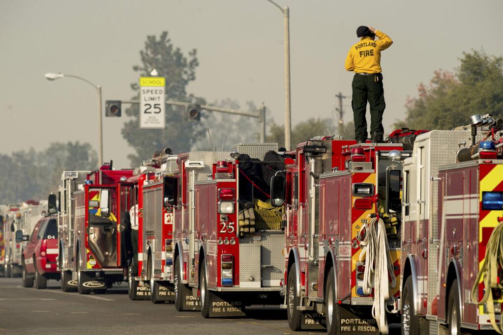 Firefighter Mike Warren, part of a Portland, Ore., crew, battling the Thomas fire, stages in Ojai, Calif., on Thursday, Dec. 7, 2017. The biggest and most destructive of the windblown fires raking Southern California shut down one of the region's busiest freeways Thursday and threatened Ojai, a scenic mountain town dubbed 'Shangri-La' and known for its boutique hotels and New Age spiritual retreats.(AP Photo/Noah Berger)