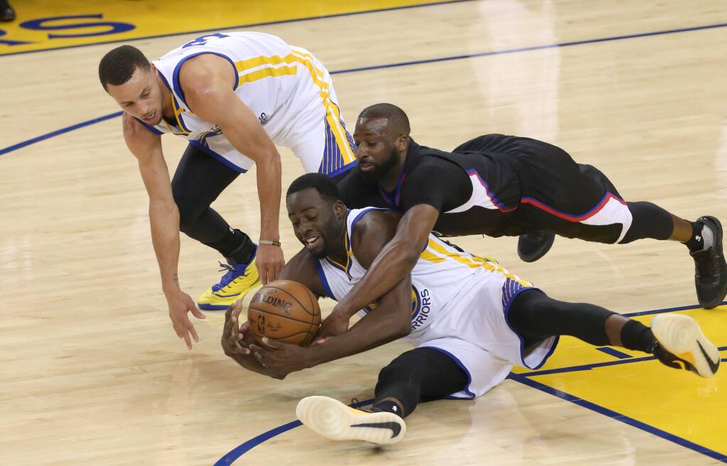 Golden State Warriors Draymond Green and Stephen Curry battle for a loose ball against Los Angeles Clippers Raymond Felton in Oakland on Thursday, February 23. (Christopher Chung/ The Press Democrat)
