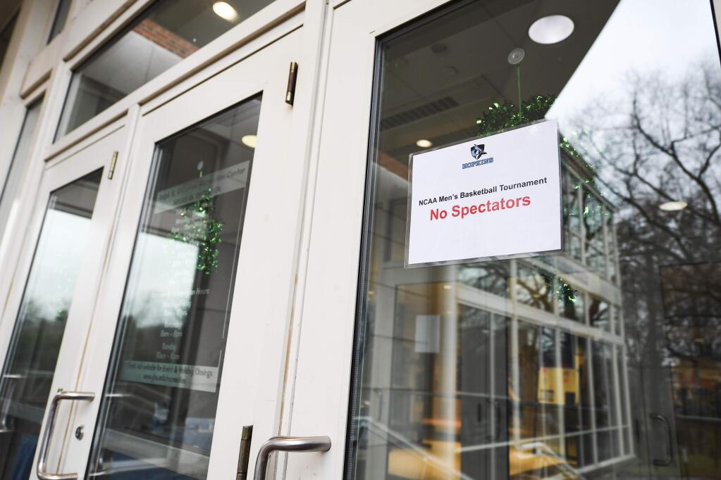 A no-spectators sign is tapped to a door at Goldfarb Gymnasium on the campus of Johns Hopkins University before a first-round game in the men's Division III NCAA tournament, between Worcester Polytechnic Institute and Yeshiva University, Friday, March 6, 2020, in Baltimore. (AP Photo/Terrance Williams)