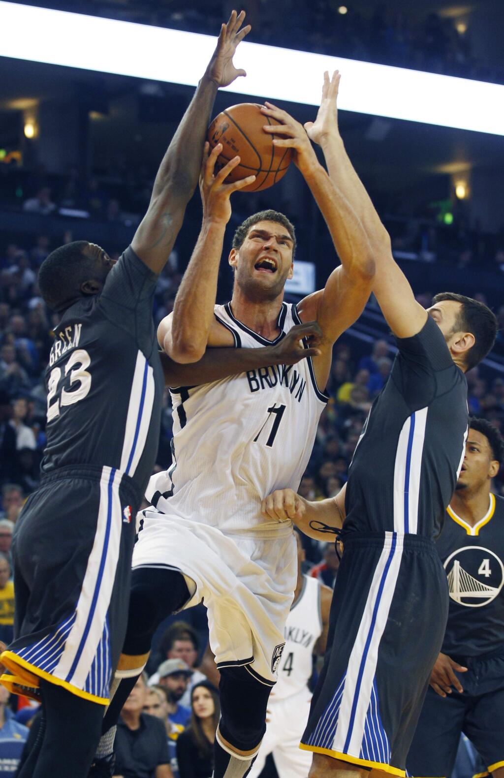 Brooklyn Nets' Brook Lopez, center goes up between Golden State Warriors' Draymond Green, left, and Andrew Bogut during the first half of an NBA basketball game, Saturday, Nov. 14, 2015, in Oakland, Calif. (AP Photo/George Nikitin)