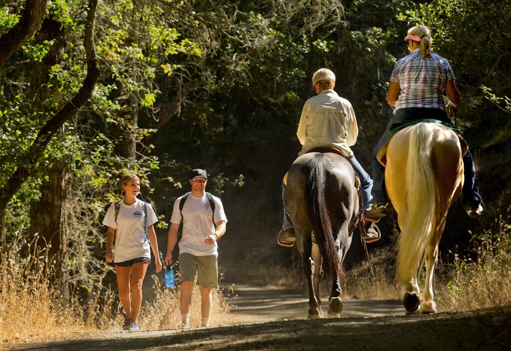 (l to r) Hikers Mattie Johnson and Nate Kitchen of Santa Rosa share a smile and a hello with equestrians Katherine Lane and Tammi Bernd of Sonoma at Trione-Annadel State Park in Santa Rosa. (JOHN BURGESS/ PD FILE, 2016)