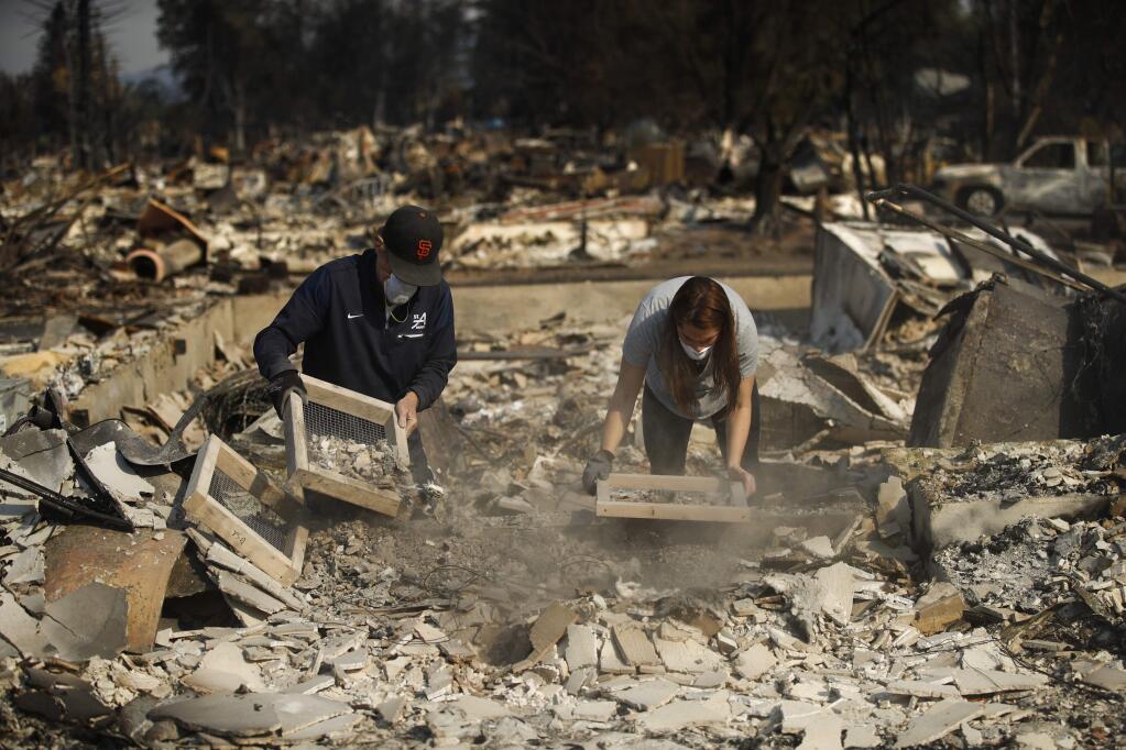 Ed Curzon, left, and his daughter, Margaret, sift debris to salvage anything they can from the rubbles of their home that was destroyed by a wildfire in the Coffey Park neighborhood Sunday, Oct. 15, 2017, in Santa Rosa, Calif. 'This is our home. This is where we grew up. This is where our kids grew up,' said Curzon. 'We will rebuild here.' (AP Photo/Jae C. Hong)