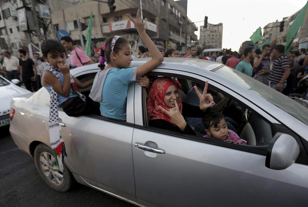 A Palestinian family flashes victory signs as they celebrate the cease-fire between Palestinians and Israelis at the main road in Gaza, in the northern Gaza Strip, Tuesday, Aug. 26, 2014. Israel and Hamas agreed Tuesday to an open-ended cease-fire, halting a seven-week war that killed more than 2,200 people, the vast majority Palestinians, left tens of thousands in Gaza homeless and devastated entire neighborhoods in the blockaded territory. (AP Photo/Adel Hana)